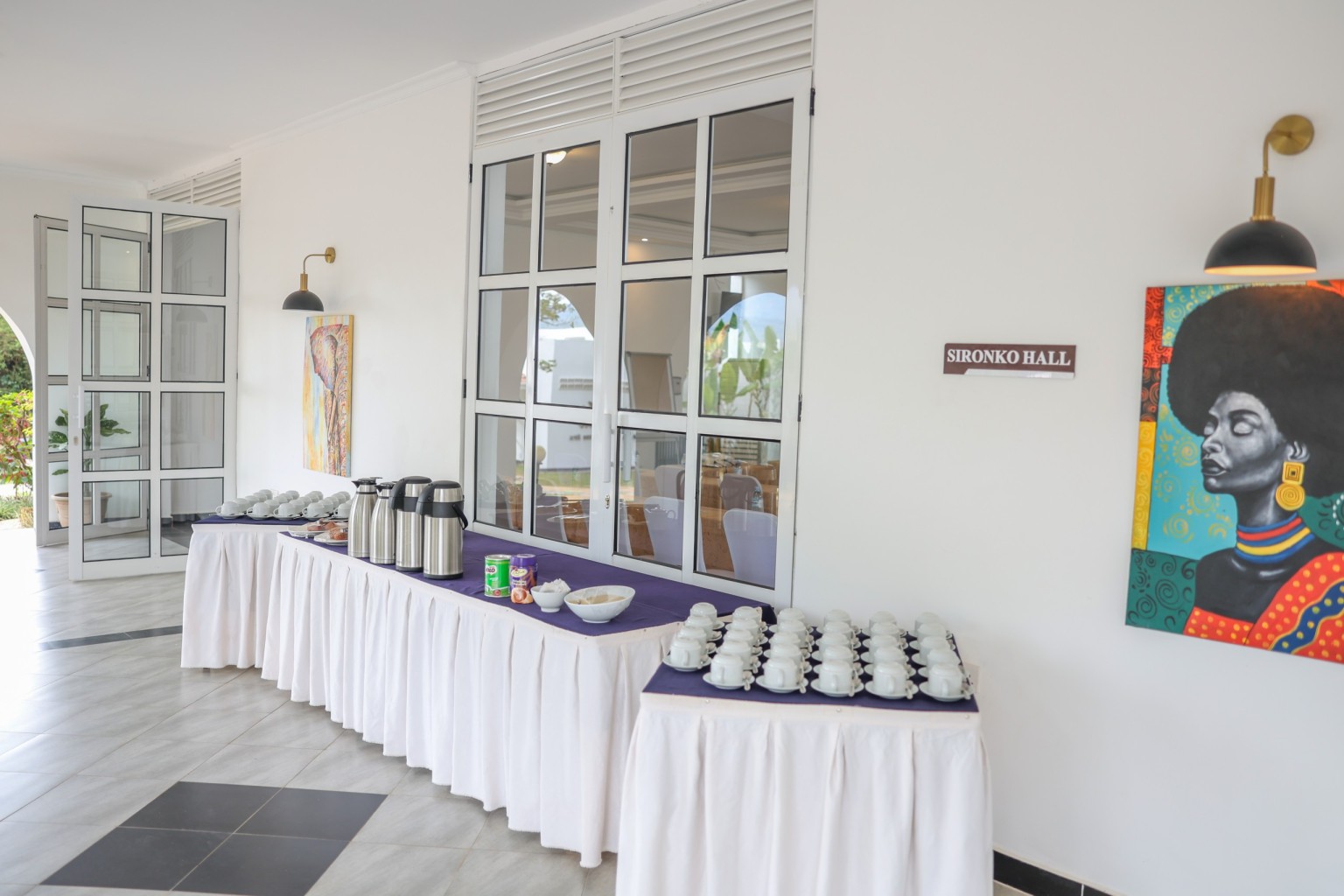 A dressed table of cups, saucers and vacuum flasks set for a conference tea break.