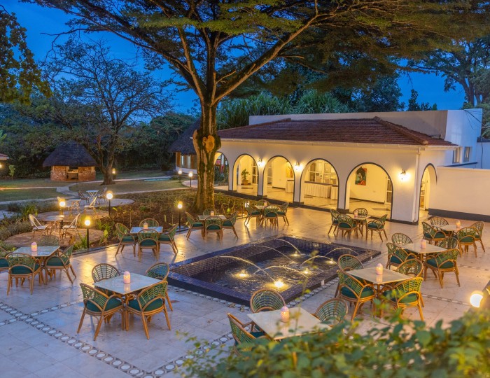 Candlelit tables on the courtyard terrace at blue hour, the arcades glowing behind.