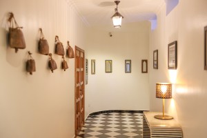 A row of hanging cowbells mounted along a white corridor wall.