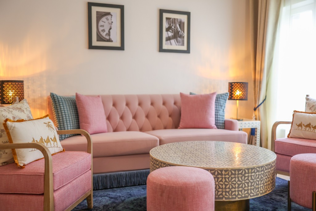 The sitting room of an Executive Suite: a pink buttoned sofa, two armchairs and a patterned round coffee table.