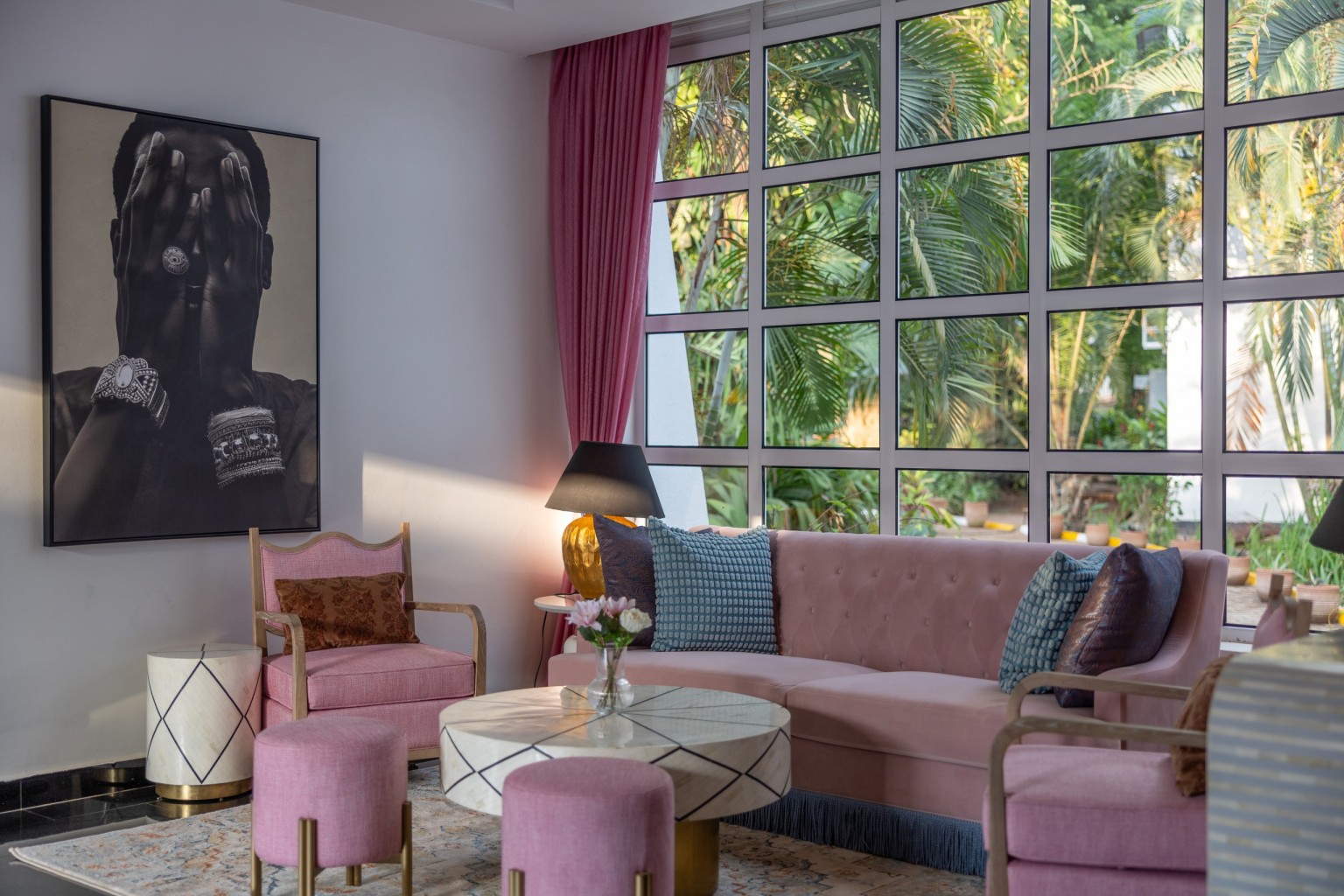 A long sofa, armchairs and side tables in the lobby lounge, portrait artwork on the wall.