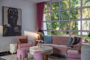 A long sofa, armchairs and side tables in the lobby lounge, portrait artwork on the wall.