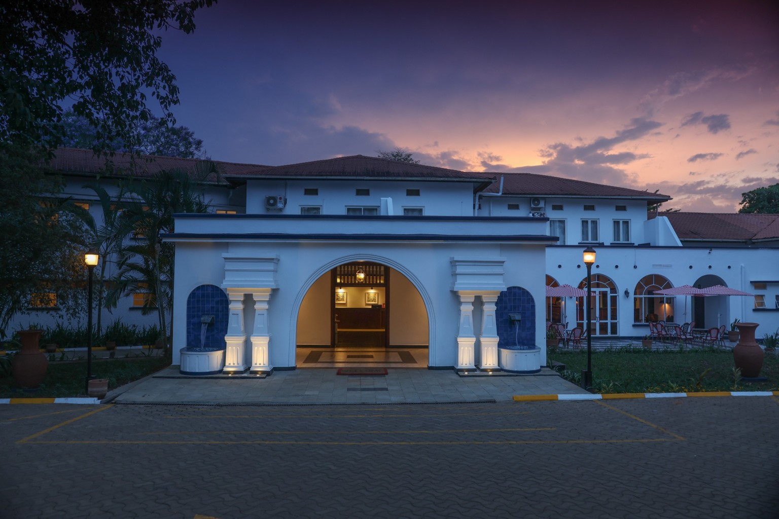 The symmetrical front elevation at night, the tall central entrance arch glowing amber.