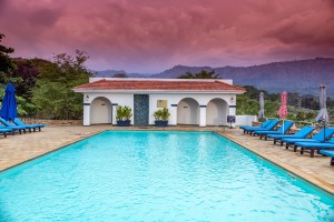 The turquoise pool and pavilion under a pink and violet sunset sky.