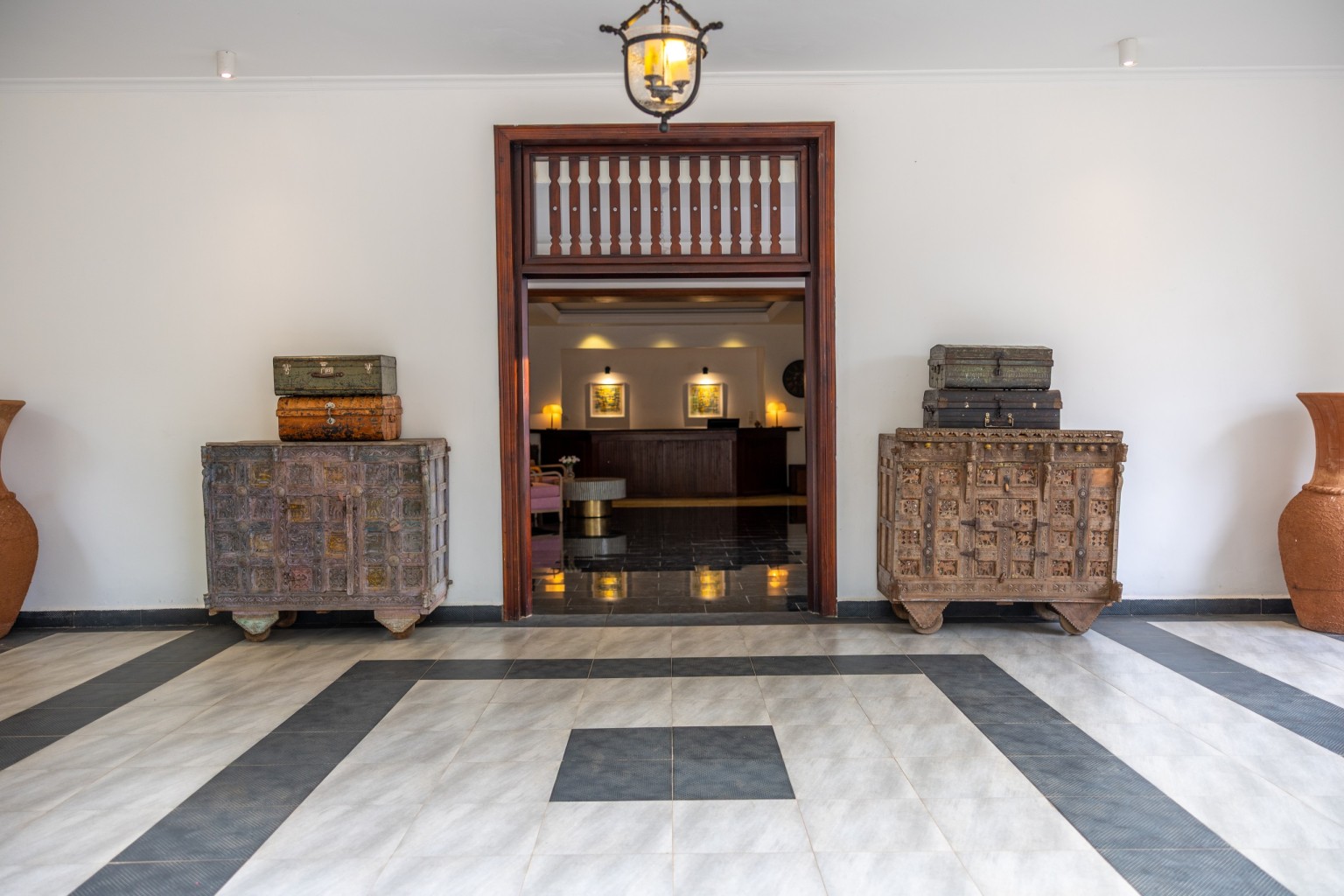 The reception desk framed by a timber doorway, painted chests either side.