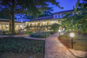 Candlelit tables and a lit water feature on the courtyard terrace at blue hour, the arcades glowing behind.