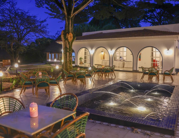 Candlelit tables around the lit courtyard water feature at blue hour, the arcades glowing behind.