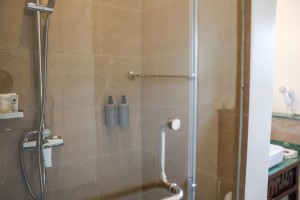 An en-suite bathroom with basin, mirror and a glazed shower, tiled in green marble.