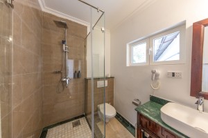 An en-suite bathroom with a glazed walk-in shower, twin basins and a marble-tiled floor.