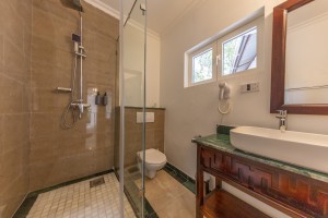 An en-suite bathroom with a glazed walk-in shower, twin basins and a marble-tiled floor.