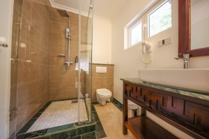 An en-suite bathroom with a glazed walk-in shower, twin basins and a marble-tiled floor.