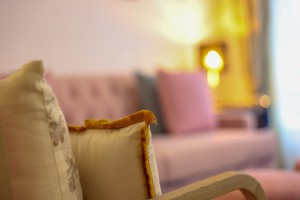 A guest room with sofa seating, writing desk, television and a window onto the garden.