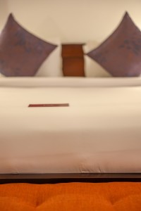 A guest room with sofa seating, writing desk, television and a window onto the garden.