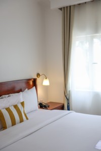 A guest room with king or twin beds, bedside lamps and curtained windows onto the garden.