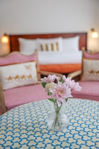 A guest room with king or twin beds, bedside lamps and curtained windows onto the garden.
