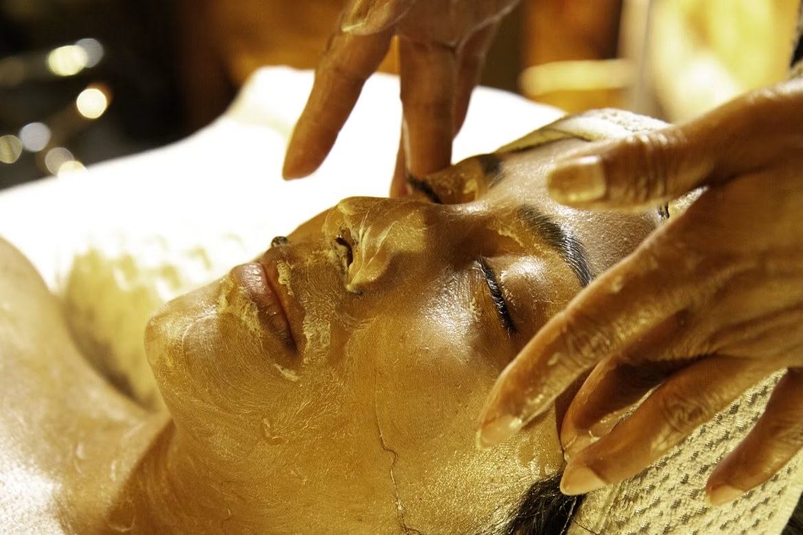 A therapist applies a facial treatment to a guest lying on a treatment bed at Kwetu Spa, lit warmly from the side.