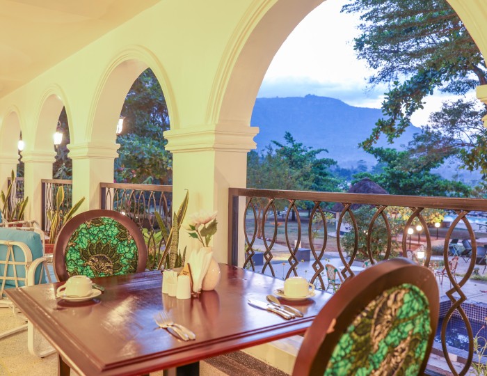 A table laid on the arched veranda of Masaaba Restaurant, the hills visible through the archway.