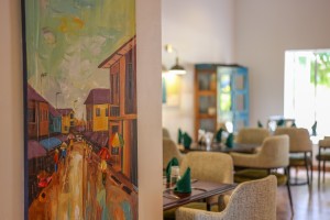 The dining room with its painted palm mural, teal napkins and carved timber furniture.