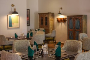 The dining room with its painted palm mural, teal napkins and carved timber furniture.