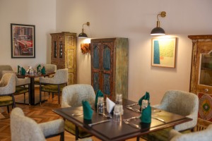 The dining room with its painted palm mural, teal napkins and carved timber furniture.