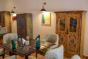 The dining room with its painted palm mural, teal napkins and carved timber furniture.