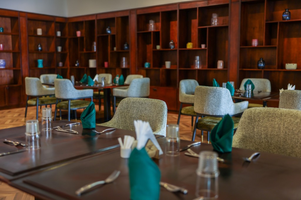 A timber-shelved room with a table laid in the foreground and further tables set behind it.