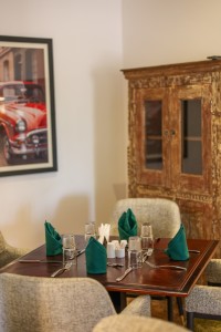 The dining room with its painted palm mural, teal napkins and carved timber furniture.