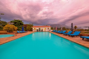 The lit pool and pavilion at dusk, with garden furniture on the terrace.