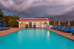 The lit pool and pavilion at dusk, with garden furniture on the terrace.