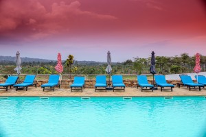 The outdoor pool and its arched pavilion under a sunset sky, blue loungers along the terrace.