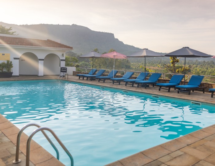 The full length of the swimming pool with loungers and parasols along one side and the escarpment beyond.