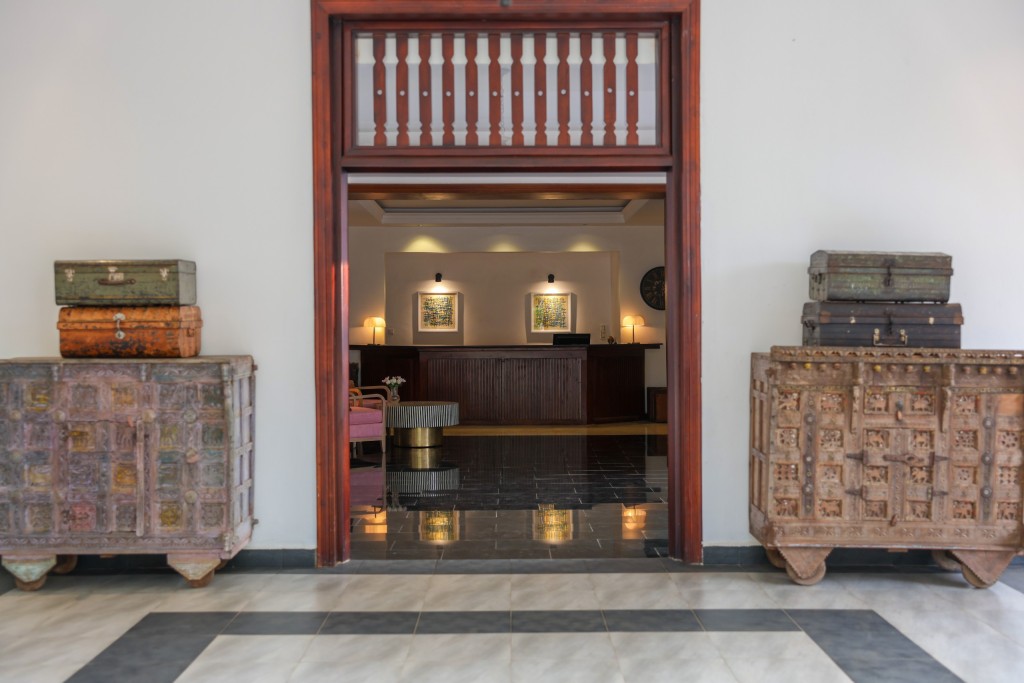 The reception desk seen through a tall timber doorway, a carved chest standing either side.