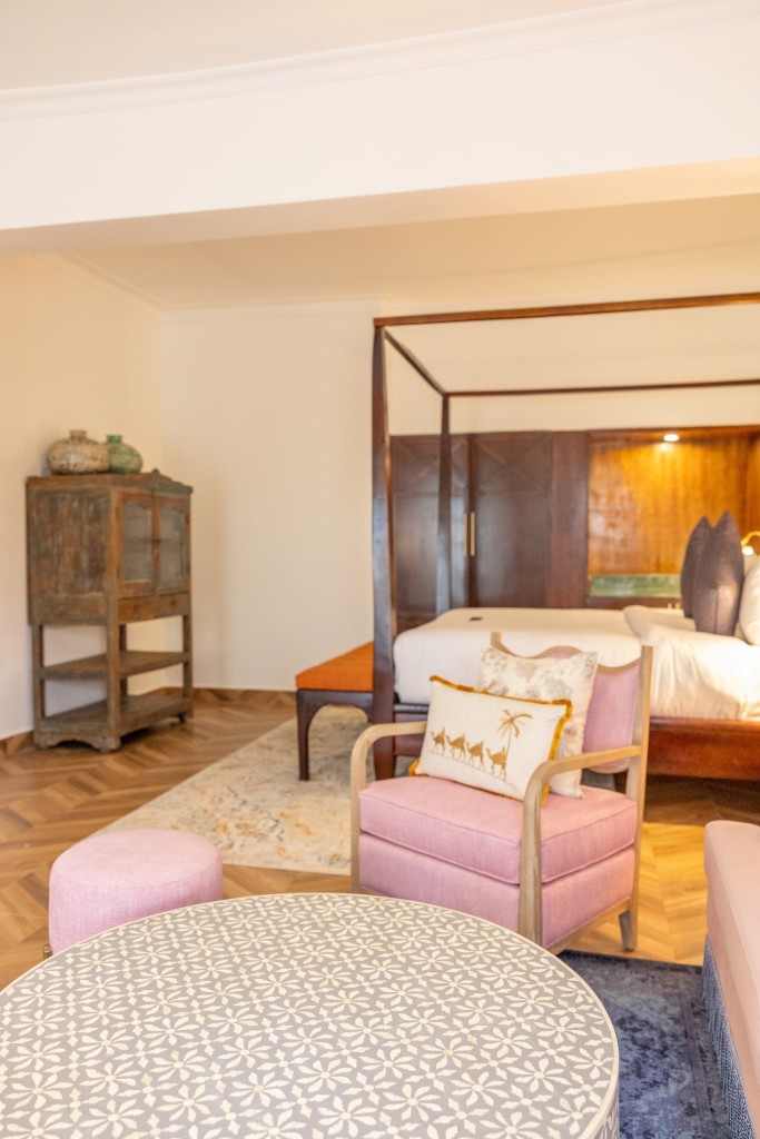An Executive Suite seen from the sitting end, with the four-poster bed at the far wall and a carved painted cabinet beside it.