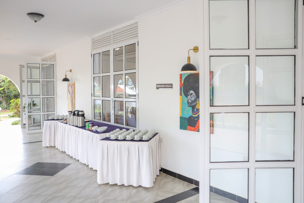 A skirted refreshment table set with flasks and cups, seen through open glazed doors from the meeting room.