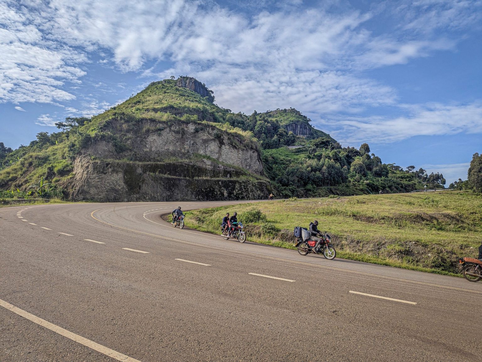 A tarmac road curving around a green hill in the Kapchorwa highlands.